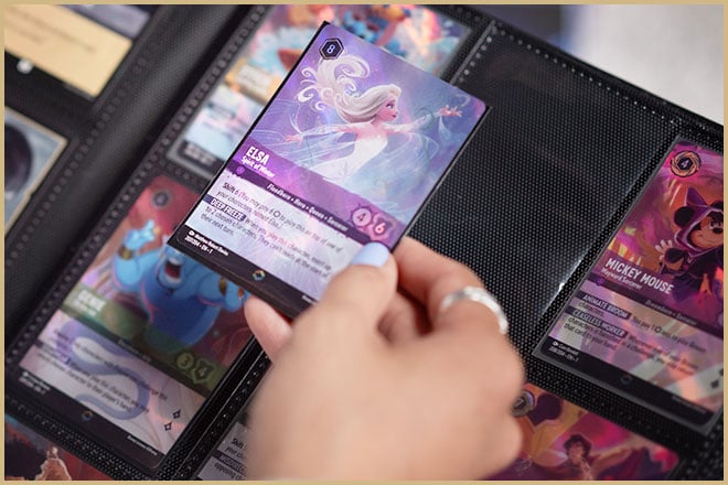 A hand holds a Disney Lorcana Trading Card Game card of Elsa.