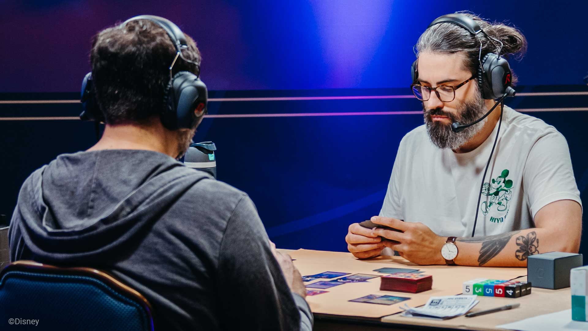 Two players playing Disney Lorcana TCG. One has a salt and pepper beard.