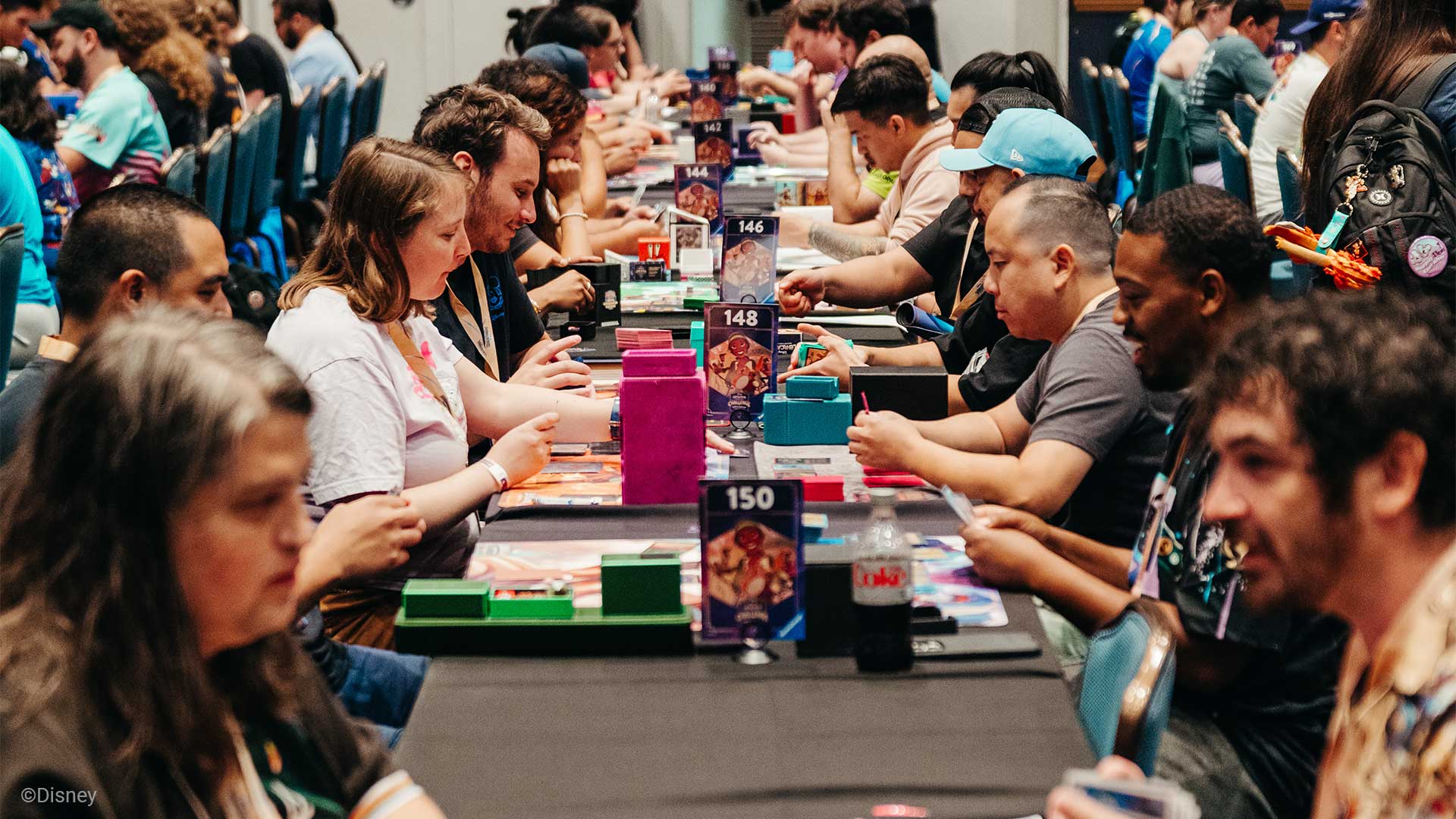 Several people playing Disney Lorcana TCG at a long table