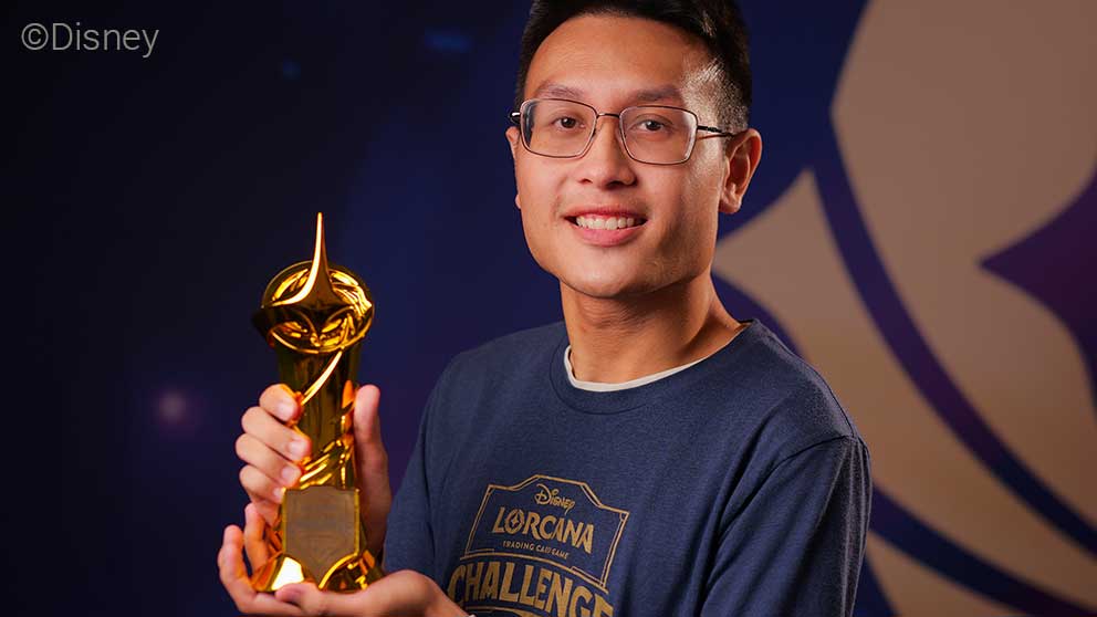 Dillon LeDuc winner of the Disney Lorcana Challenge North America Championship. He holds a golden trophy and smiles for the camera.